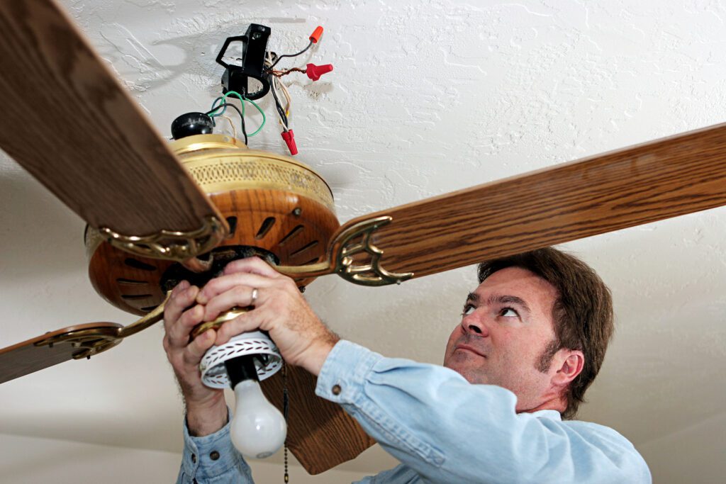 A person removing a ceiling fan at home