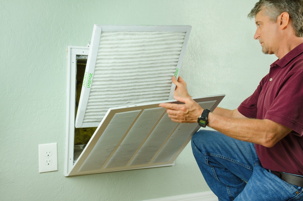 Home Owner Putting New Air Filter On Air Conditioner