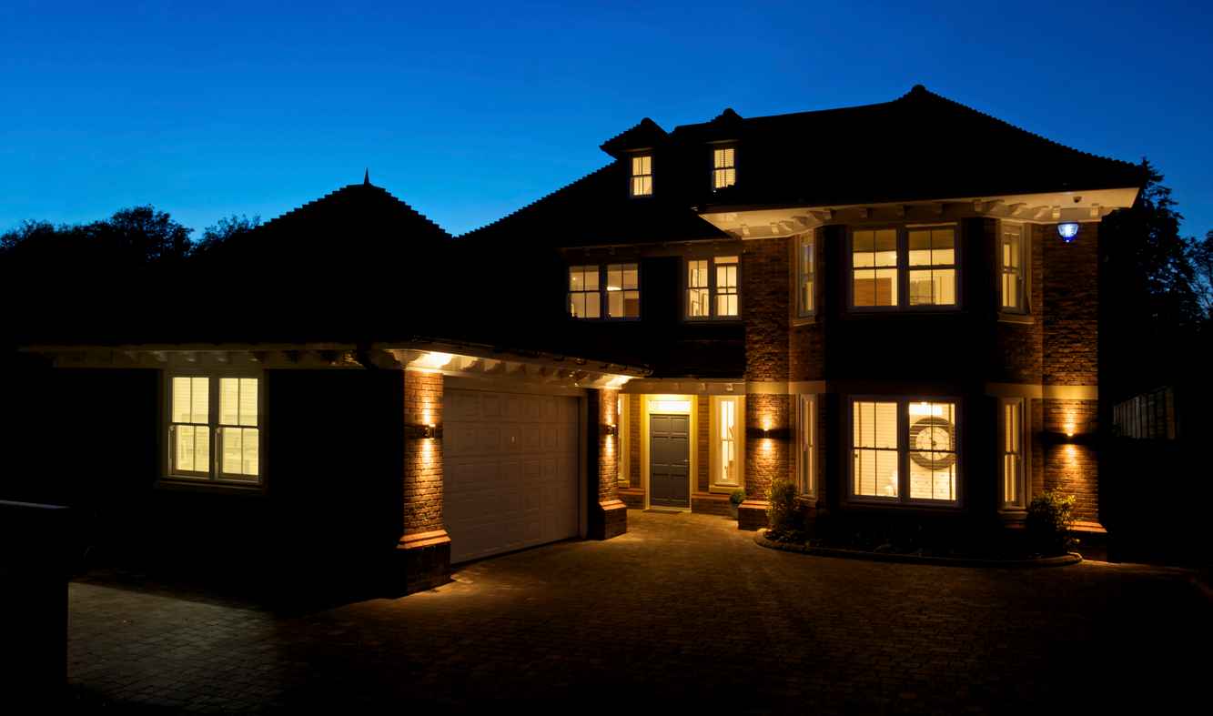 a view of a new house taken after sunset with all of the internal and exterior lights switched on.